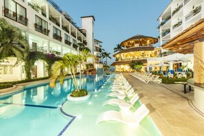 A hotel pool area with lounge chairs, a pool, and a restaurant with outdoor seating. - Playa Los Arcos Resort & Spa All Inclusive (Puerto Vallarta)