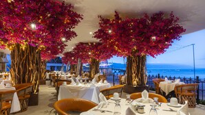 En restaurant med dækketøi ved borde, med udsigt over vandet.