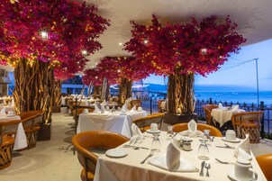 A restaurant with tables set for dining, overlooking a body of water.