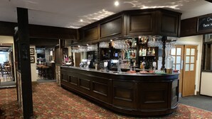 A bar area with a dark wood counter, multiple bar tools, and a variety of bottles and glasses. - The Bowes Incline (Chester-le-Street)