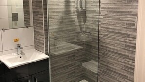 A modern bathroom with a glass-enclosed shower, a white sink, and dark cabinetry. - The Bowes Incline (Chester-le-Street)
