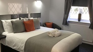 A neatly made bed with a white and grey bedspread, two rolled towels, and several pillows in various colors. - The Bowes Incline (Chester-le-Street)