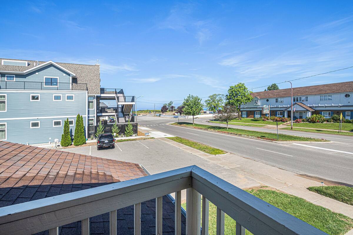 A residential street with houses, a clear sky, and a car parked on the side.