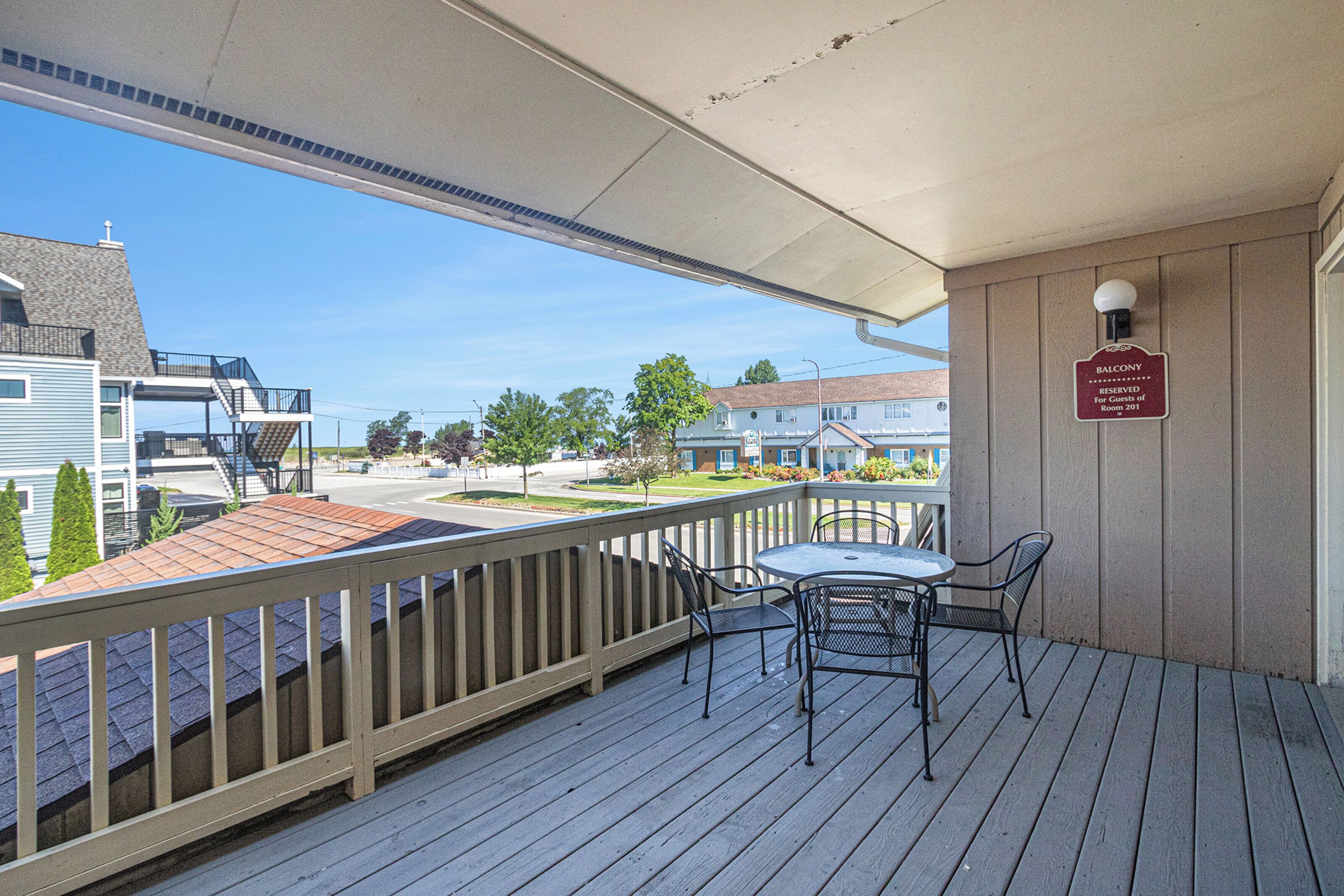 A balcony with a table and chairs, a sign indicating it is a reserved balcony, and a view of the street and other buildings.