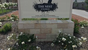 Placa para 'The Nest at Gundaroo' indicando acomodação de luxo para estadias curtas, com informações de contato e site.