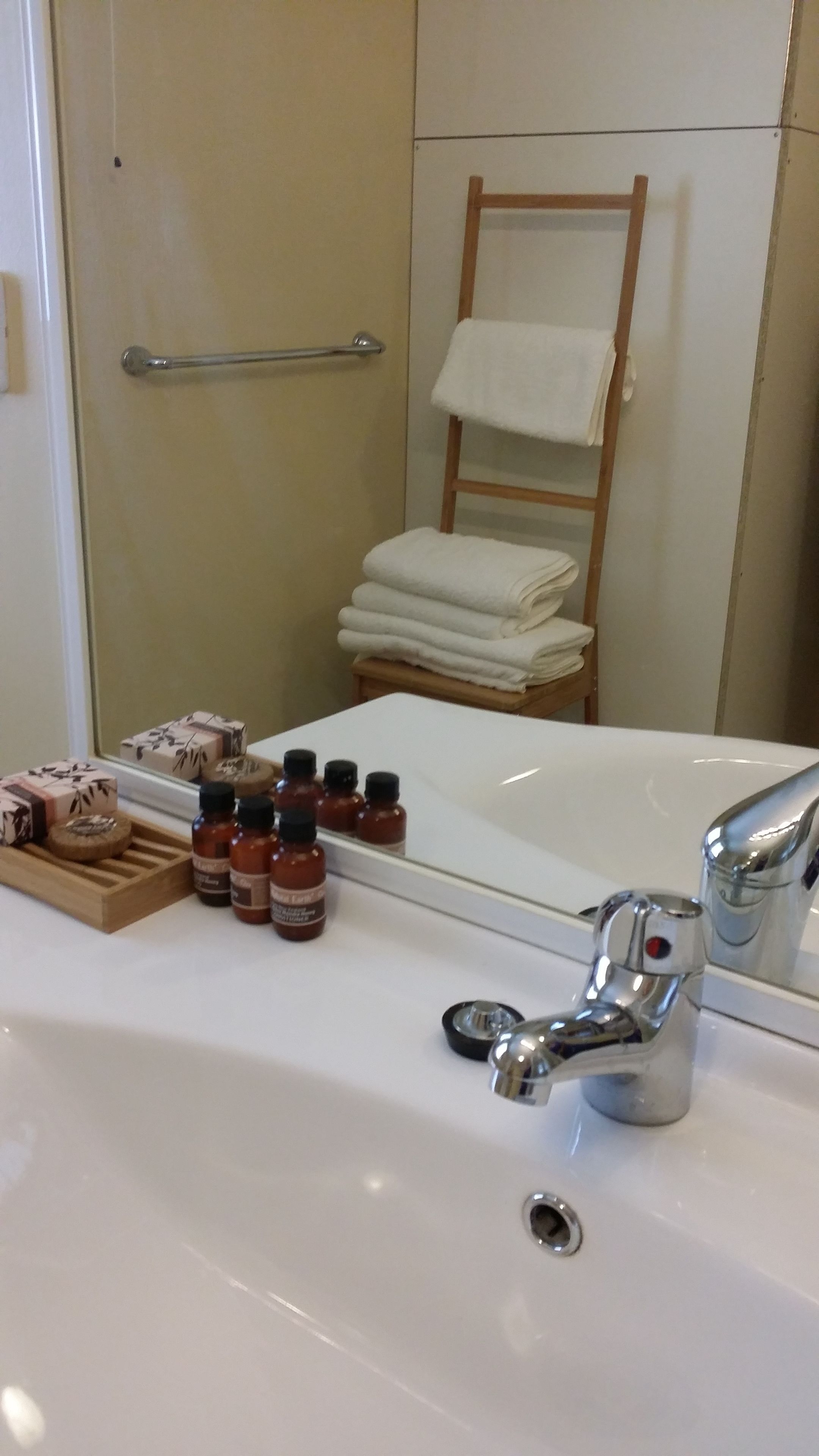 A bathroom with a white bathtub, a chrome faucet, and a wooden shelf with toiletries.