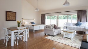 Uma sala de estar ampla com área de jantar, cama e uma grande janela com cortinas.