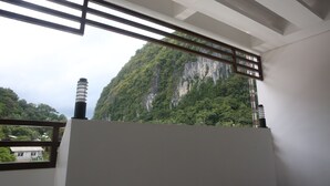A room with a view of a mountainous landscape through a window with wooden blinds. - Den'gi Inn (El Nido)