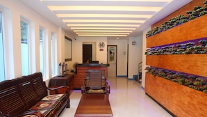 A reception area with a wooden reception desk, a bench, and a wall-mounted planter with greenery. - Den'gi Inn (El Nido)
