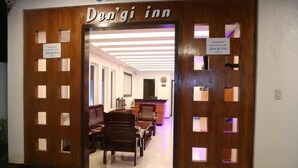 The entrance to Den'gi inn with a reception desk, seating area, and a sign indicating the inn is now open. - Den'gi Inn (El Nido)
