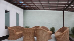 Wicker furniture in an outdoor area with a pergola overhead. - Den'gi Inn (El Nido)