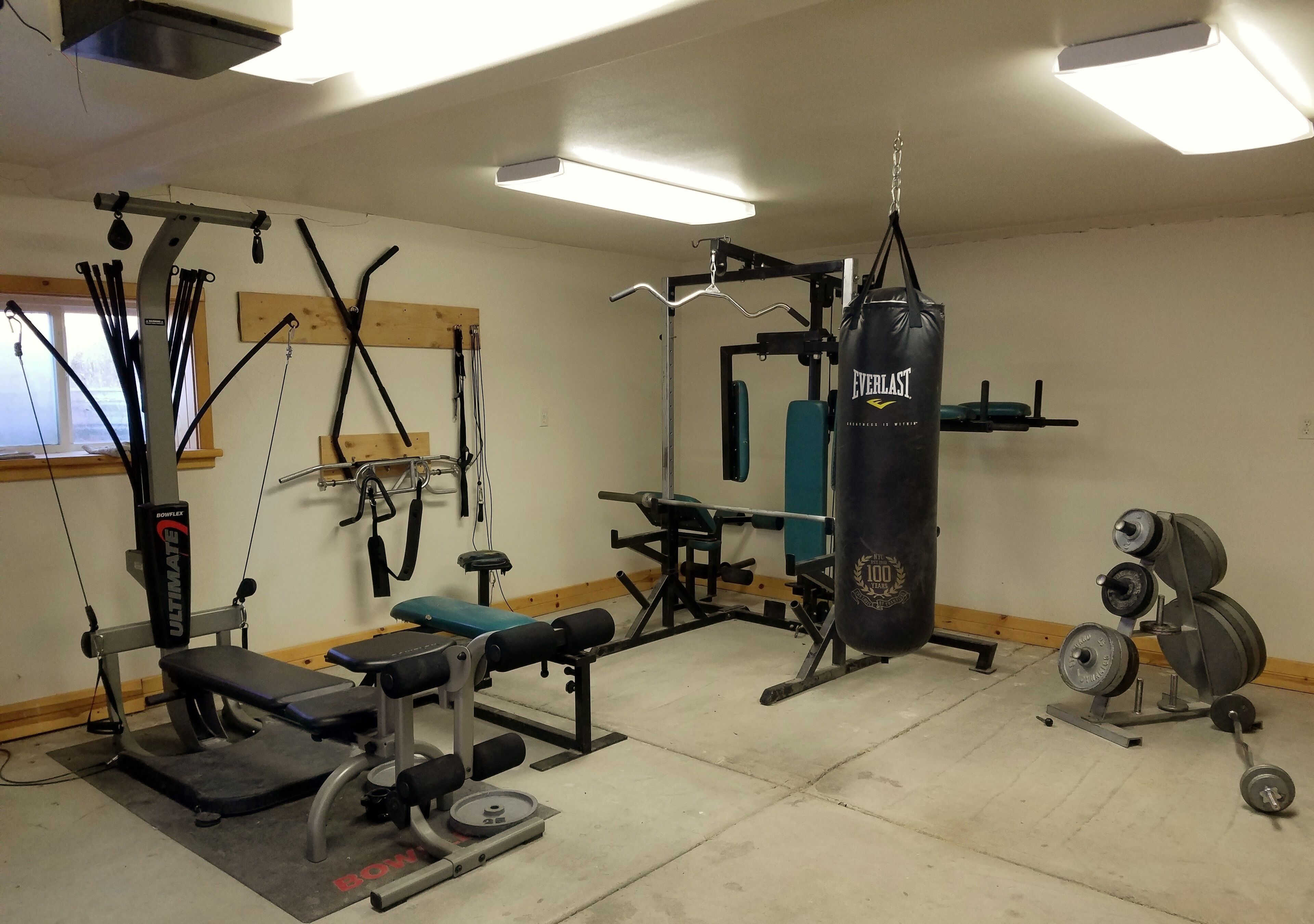 A gym with various exercise equipment including a bench press, weight racks, and a punching bag.