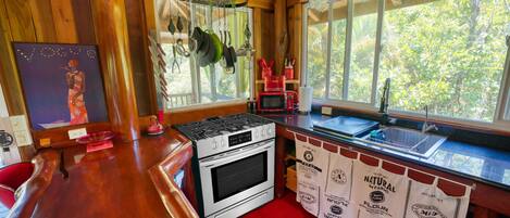 Una cocina con paredes de madera, estufa, microondas y ollas colgantes.