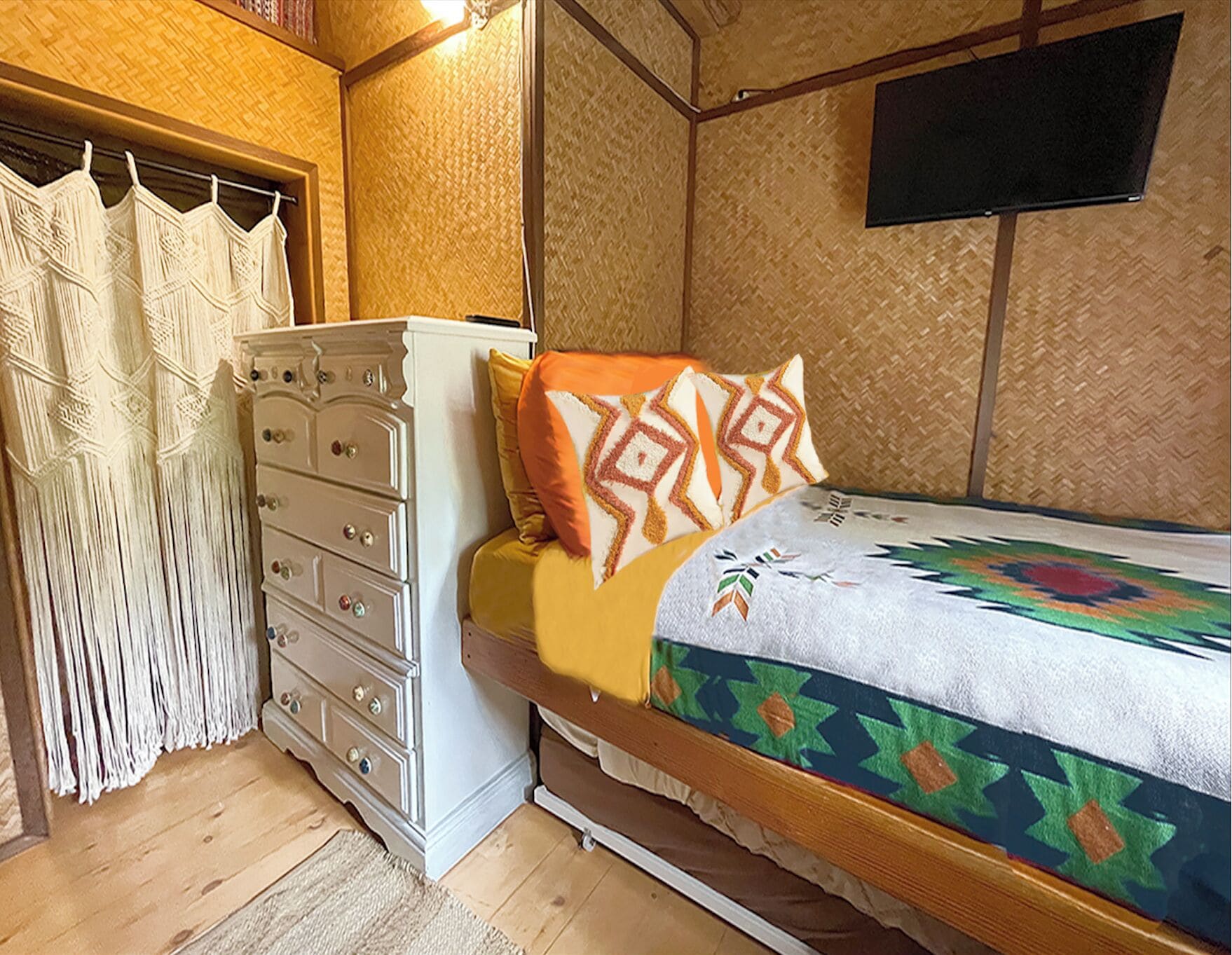 Un dormitorio con cama, cómoda, televisor y cortina.
