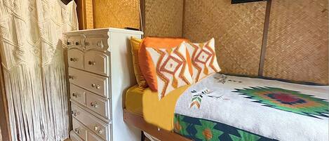 Un dormitorio con cama, cómoda, televisor y cortina.
