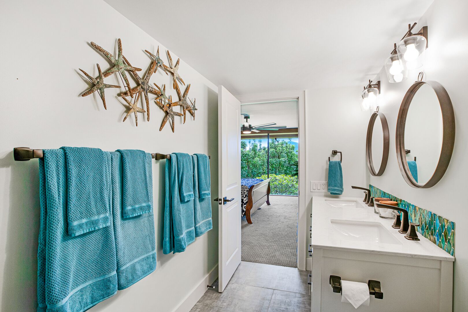 A bathroom with a white sink, two mirrors, and starfish wall art.