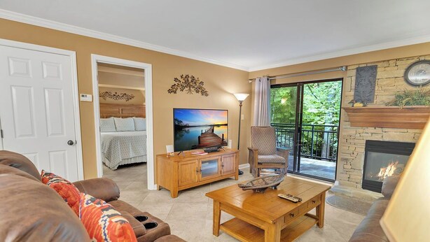 A living room with a fireplace, a sofa, a coffee table, and a TV. - two bedroom condo sleeps 4 persons (Gatlinburg)