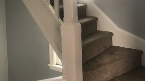 Una escalera con barandillas blancas y peldaños alfombrados.
