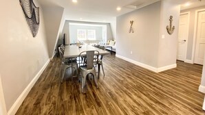 Una habitación amplia con una mesa de comedor y sillas, un sofá y un ancla decorativa en la pared.