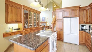 Una cocina con armarios de madera, encimera de granito, estufa blanca y refrigerador.