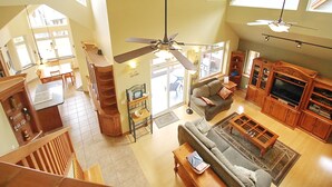 Un amplio salón con techo alto, muebles de madera y un televisor grande.