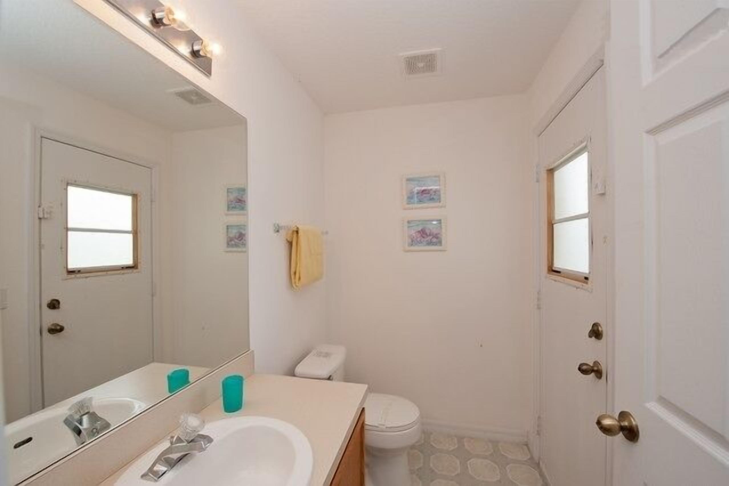 Un bagno piccolo e pulito, con un lavandino bianco, uno specchio e un WC.