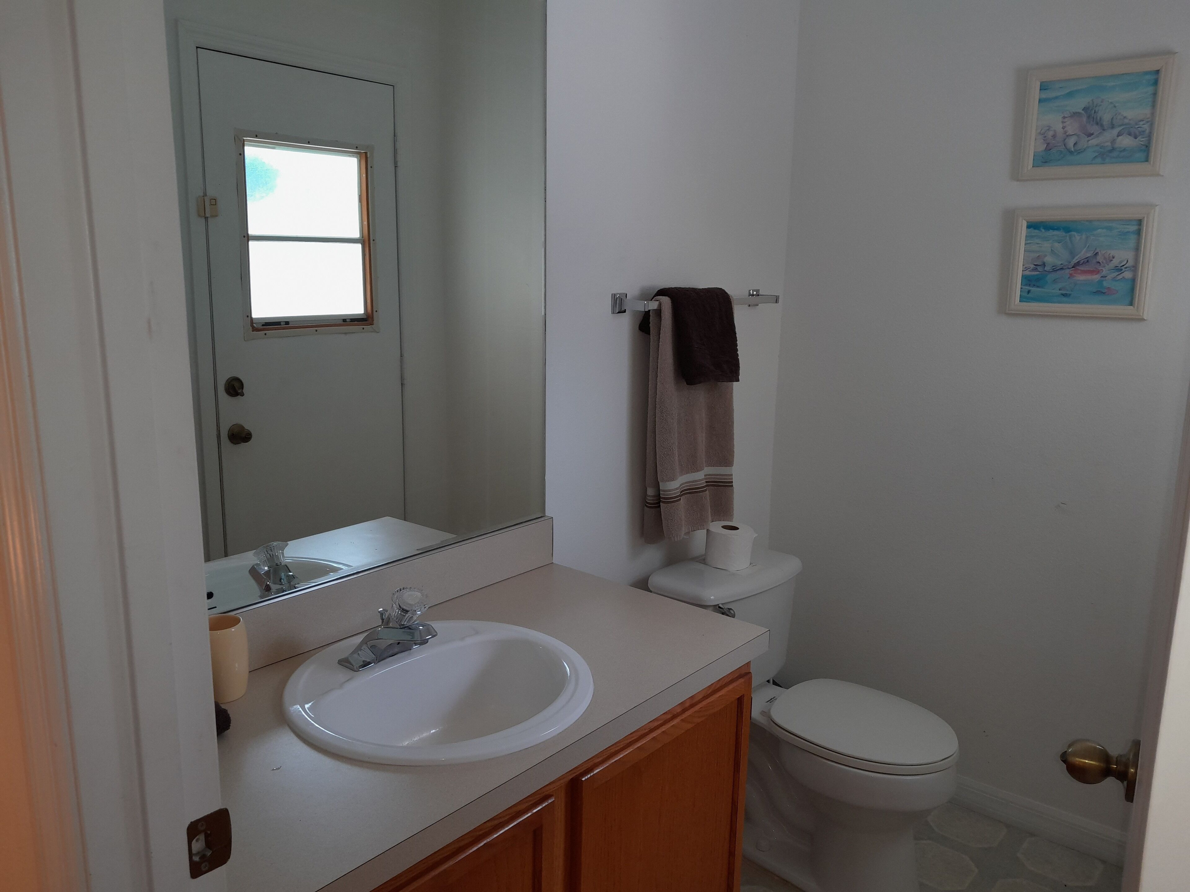 Une salle de bain avec un lavabo blanc, un miroir, des toilettes et une serviette accrochée au mur.