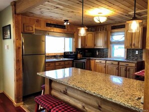 Enjoy cooking in this well-equipped kitchen with a central island, stainless steel refrigerator, and granite countertop.