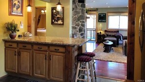 Una cocina con armarios de madera, una pared de acento de piedra y una zona de bar con taburetes.