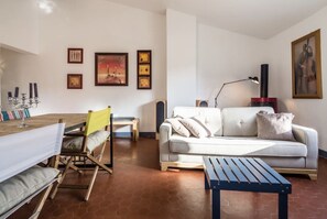 Una sala de estar con sofá, una mesa de centro, una mesa de comedor con sillas y una chimenea.