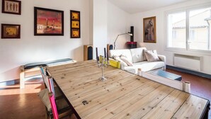 Ein modernes Wohnzimmer mit Esstisch aus Holz, einem weißen Sofa und einem großen Fenster, das für natürliches Licht sorgt.