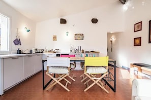 Cocina compacta con armarios blancos, una mesa de comedor y dos sillas plegables.