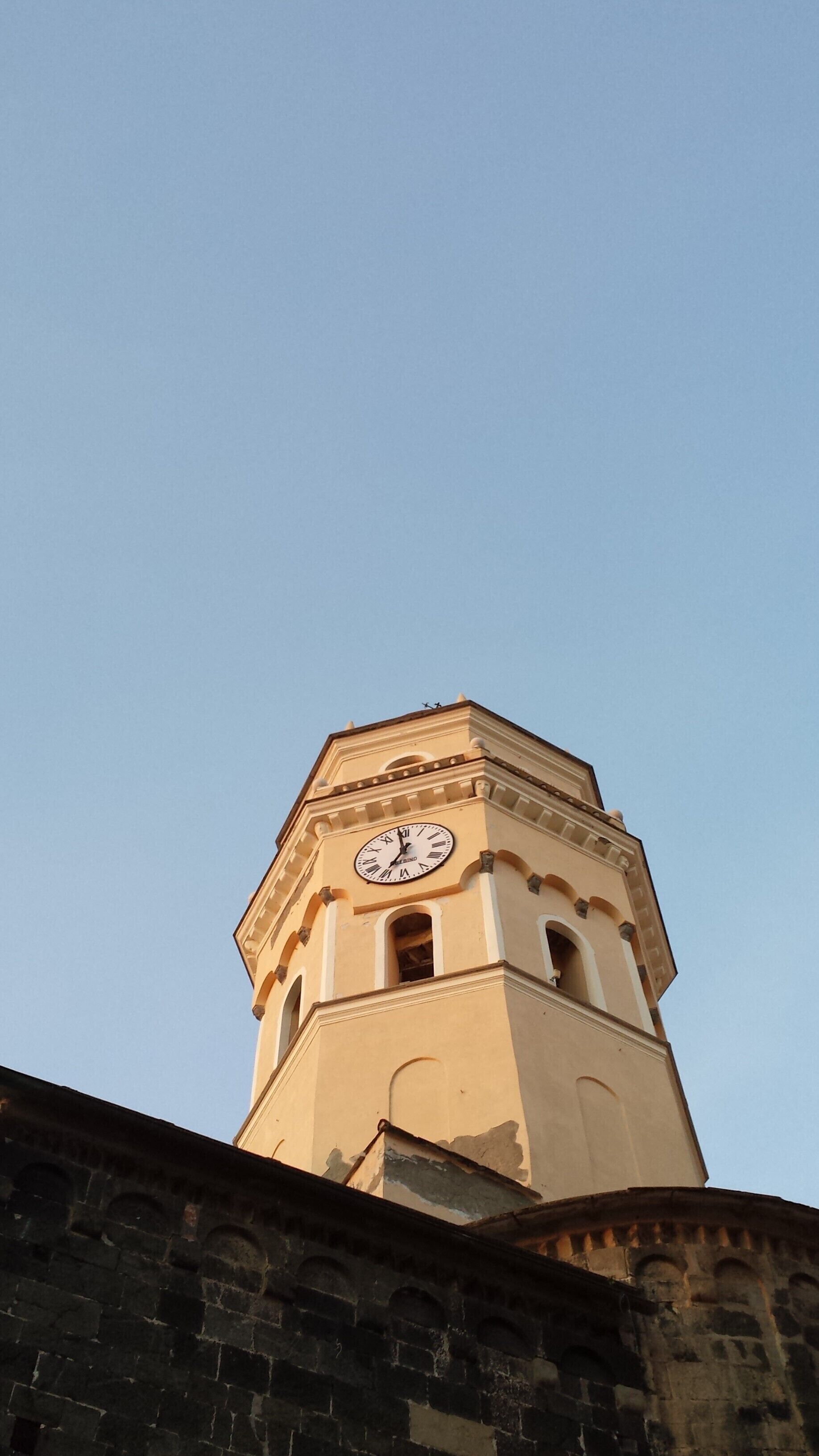 A clock tower with a clock face, surrounded by clear blue sky.