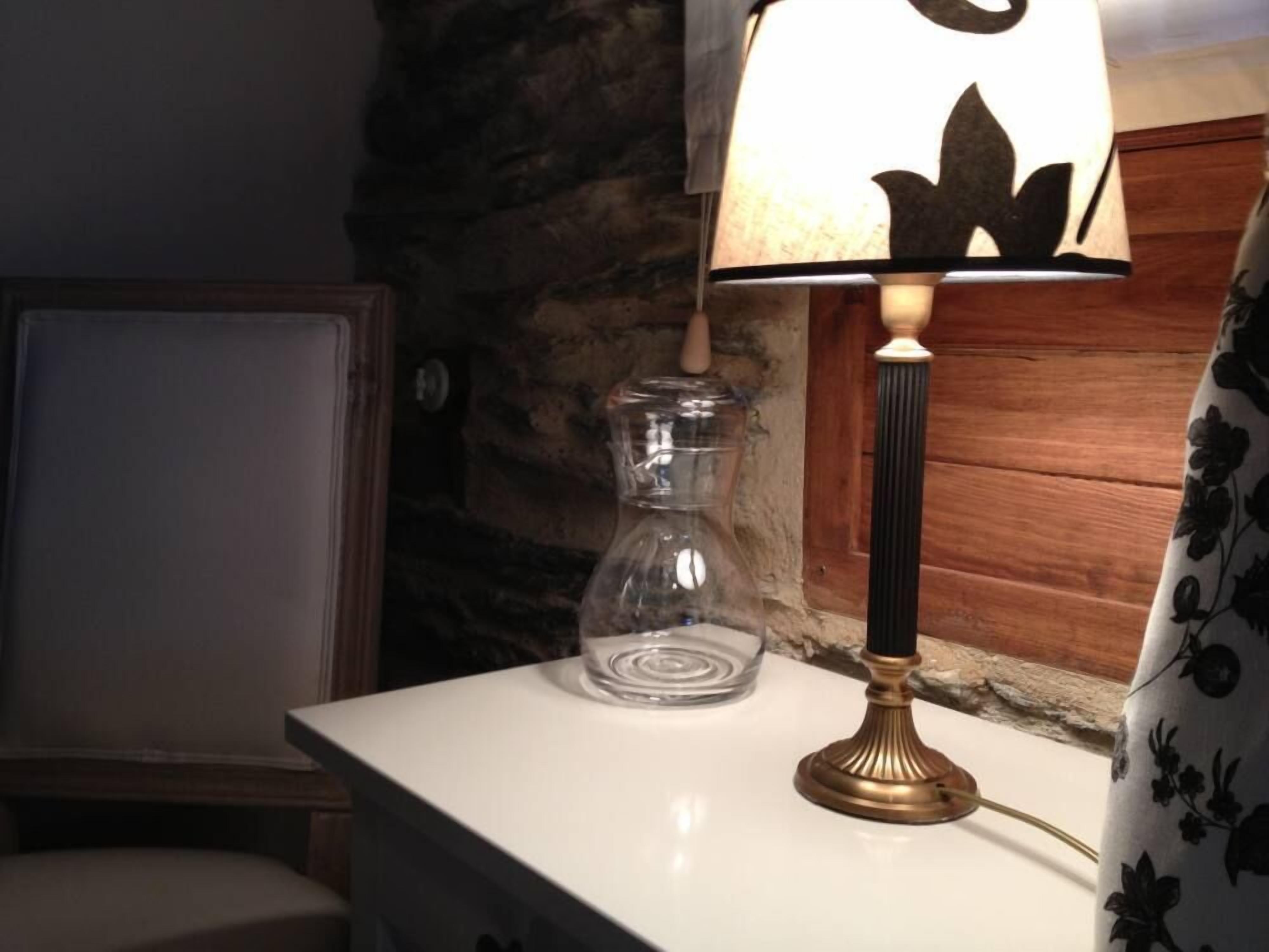 Une table sur laquelle se trouve un vase en verre transparent et une lampe avec un abat-jour à motifs floraux.