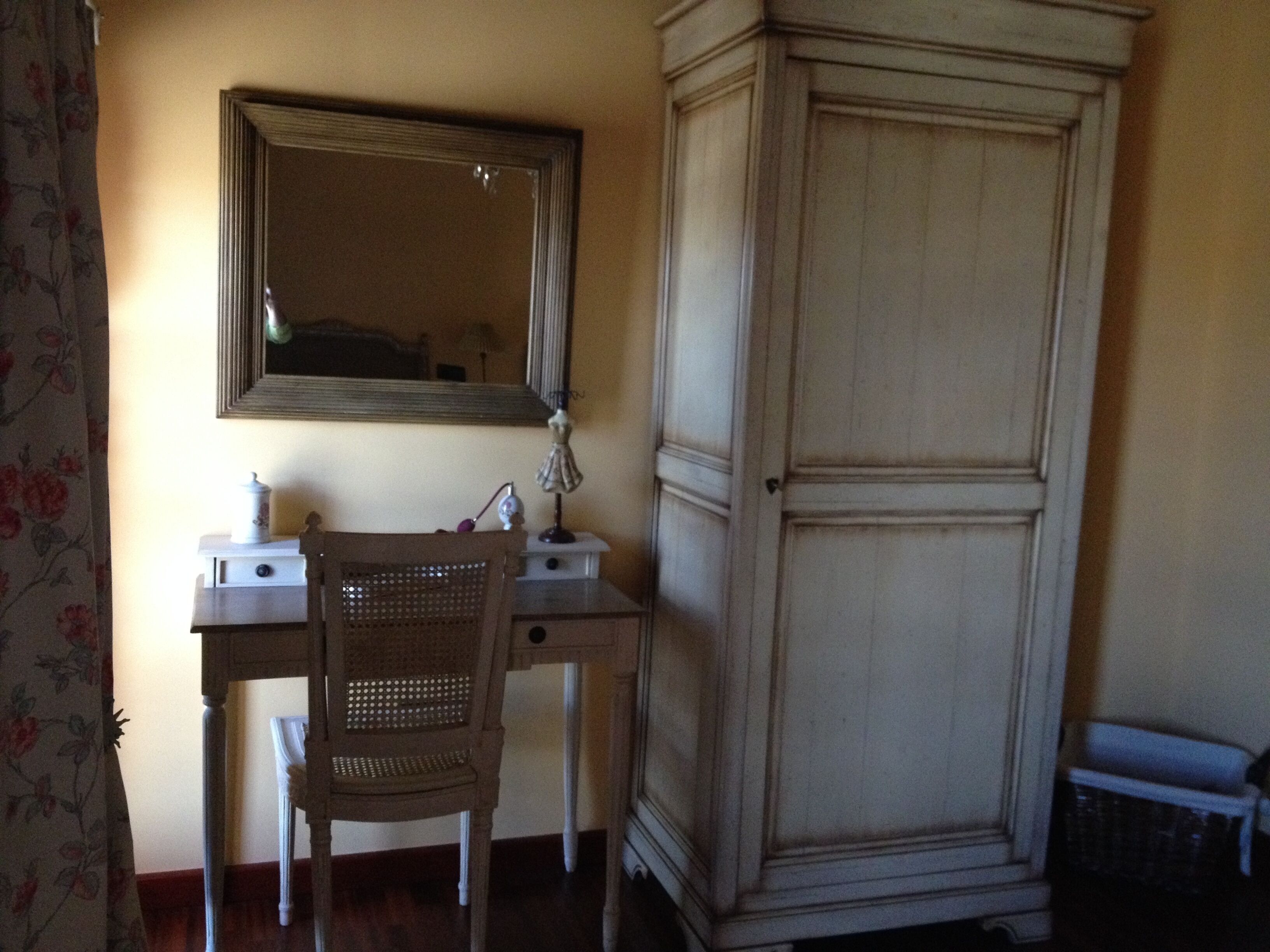 Een kamer met een houten bureau, een stoel, een spiegel en een grote kledingkast.
