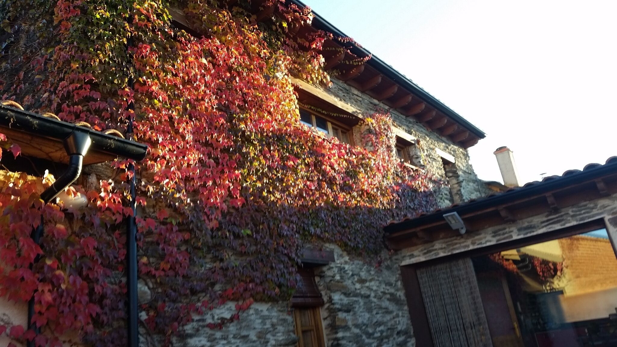 Un edificio rústico de piedra con techo de madera y una ventana con persiana de madera.