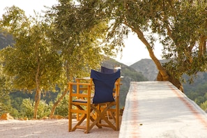 A wooden chair under a tree, overlooking a mountainous landscape. - Charming Wooden Eco-House in unspoiled nature surrounding Sougia  (Selino, Chania)