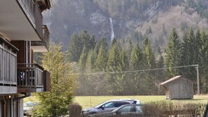 En bygning med balkon, udsigt over skov og vandfald.