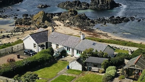 Una casa costera con un jardín grande, un garaje y vistas al mar.