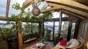 Un cuarto acogedor con techo de madera, chimenea, un sillón cómodo y vista al mar.