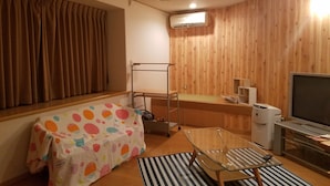 Une pièce de taille modeste, comprenant un lit, une petite table, un téléviseur et un panneau mural en bois.