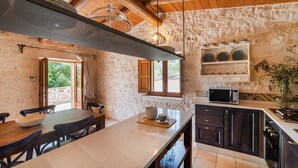 Una cocina rústica con paredes de piedra, vigas de madera, una isla grande y un estante empotrado para microondas.
