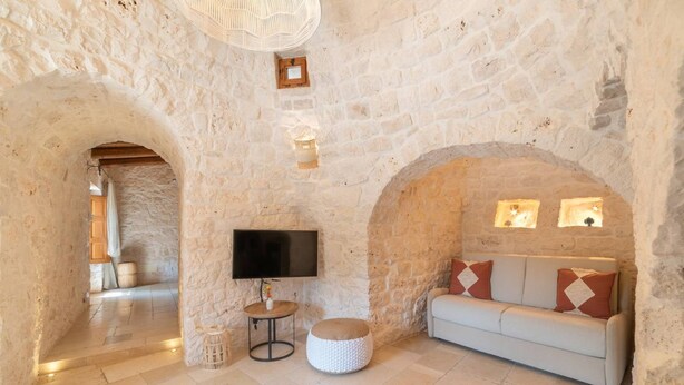 Una habitación con paredes de piedra, un sofá, un televisor y una mesita.