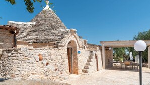 Un edificio de piedra con techo cónico, una puerta y un pequeño porche.
