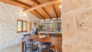 Una cocina rústica con paredes de piedra, vigas de madera y una isla grande con asientos.