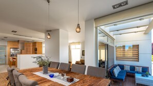 Een moderne eethoek met een houten tafel, gestoffeerde grijze stoelen en hanglampen.