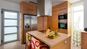 Een moderne keuken met houten kastjes, roestvrijstalen apparatuur en een centraal eiland met een fruitschaal.