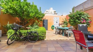 Un espace patio aménagé avec un vélo, une table, des chaises et une plante en pot.