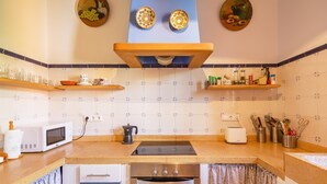 Une cuisine équipée d’un four à micro-ondes, d’un grille-pain, d’une cuisinière, d’un four et de divers ustensiles de cuisine disposés sur le plan de travail.