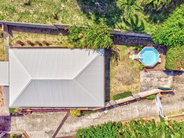 Eine Vogelperspektive eines Gebäudes mit einer großen, flachen Dachterrasse, einem Swimmingpool und umgebender Bepflanzung.